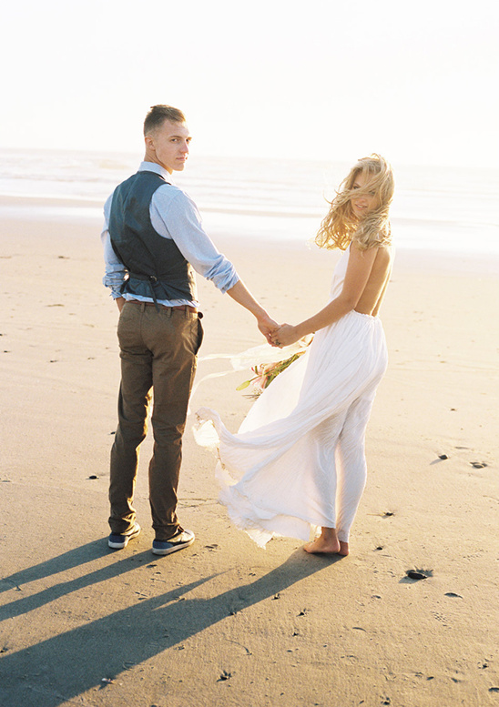 Romantic couple holding hands on the beach at sunset