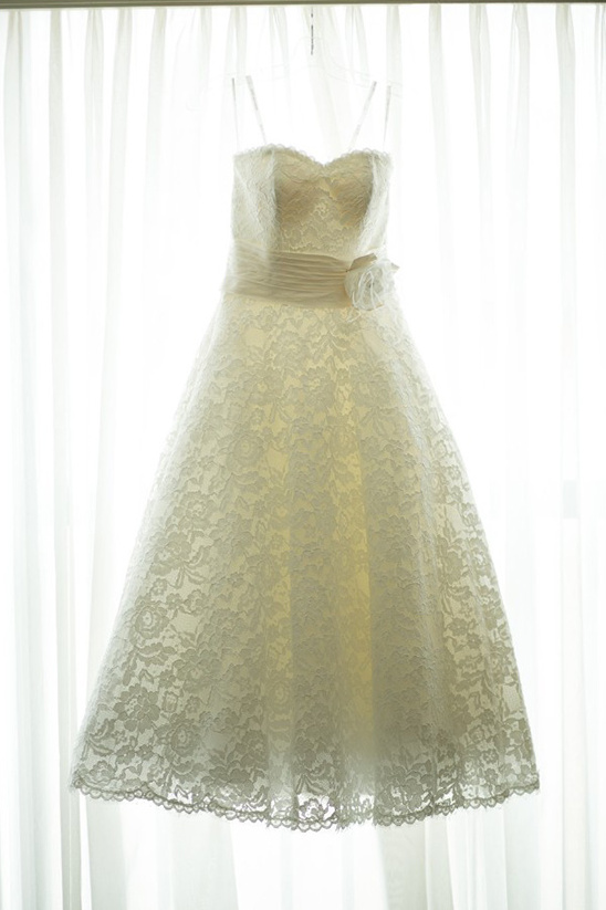Elegant lace wedding dress hanging in window light