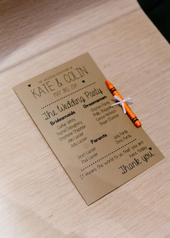 Handwritten wedding ceremony program with crayon detail on wooden table