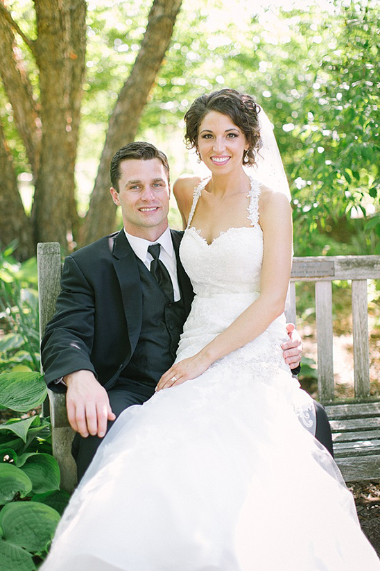 Smiling bride and groom on a bench in wedding attire
