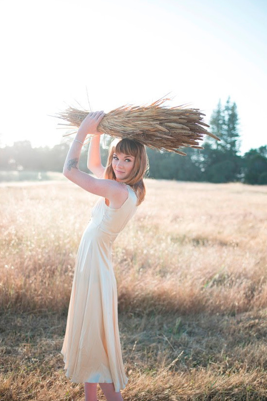 Woman in field holding wheat stalks above head