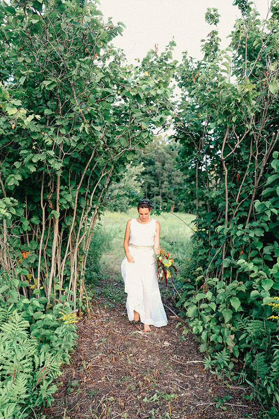Bride in white dress walking barefoot through foliage