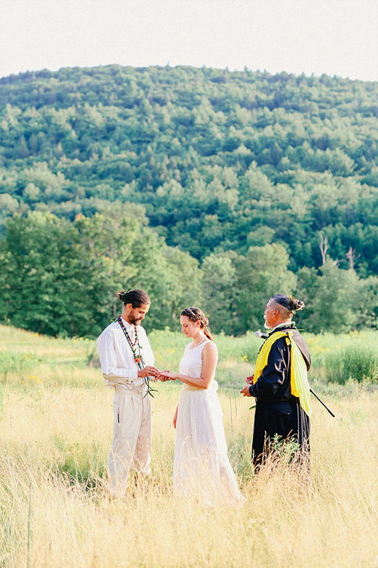 Outdoor wedding ceremony with officiant and couple exchanging rings