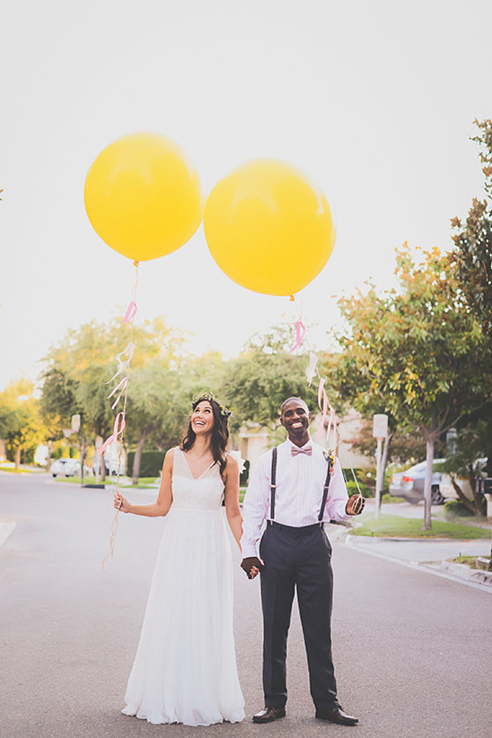 Happy couple holding yellow balloons on their wedding day