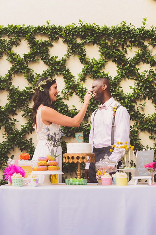 Happy couple playfully celebrating wedding with cake and sweets