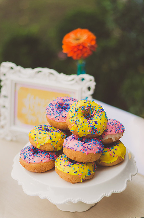 Stack of colorful sprinkle donuts on cake stand