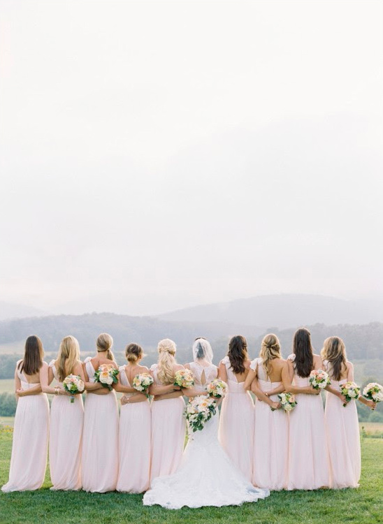 Bride and bridesmaids in pink gowns overlooking scenic mountains