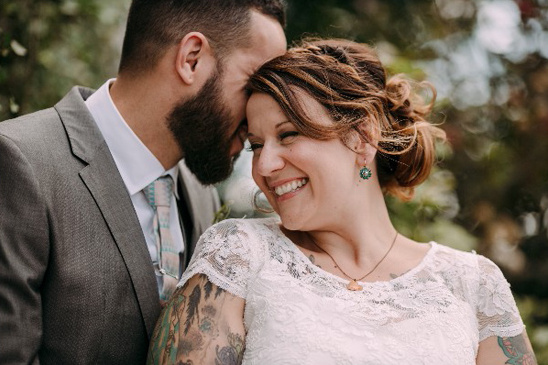 Happy bride and groom smile on wedding day, close embrace