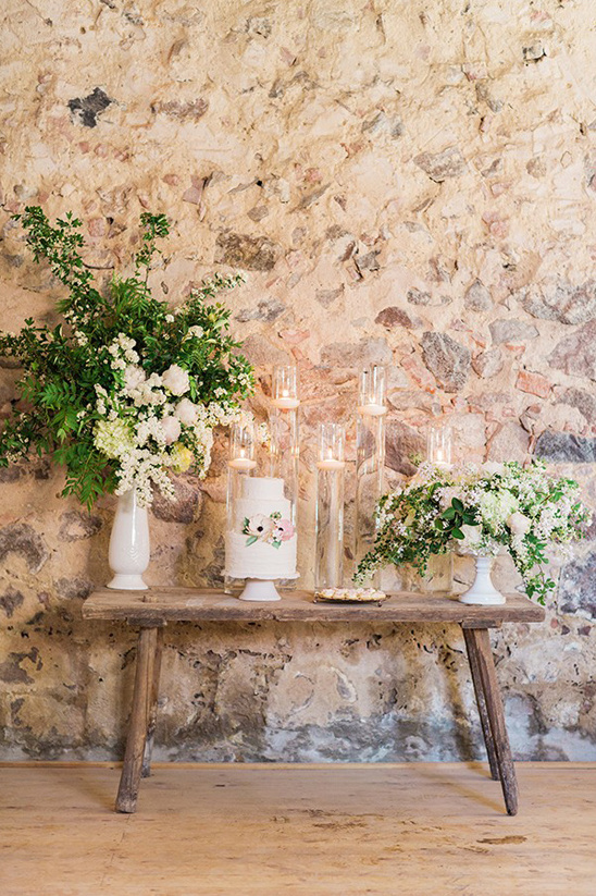 Rustic wedding decor with cake, flowers, candles, and wooden table