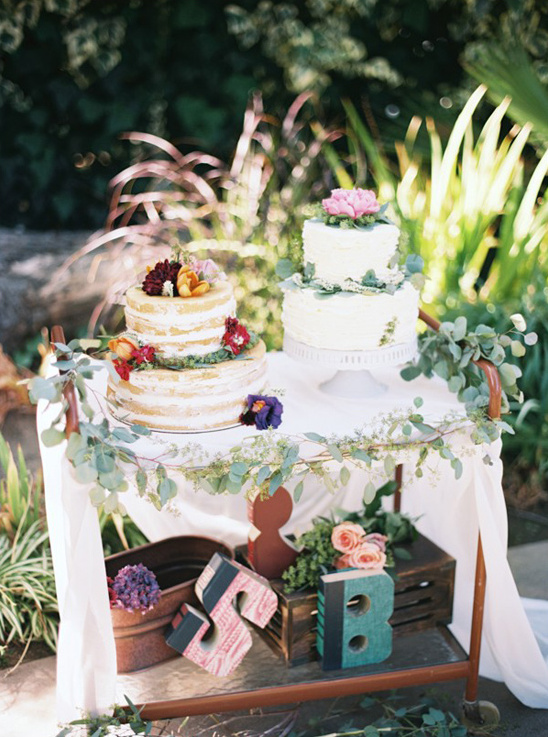 Wedding cakes with floral decor on a rustic cart display