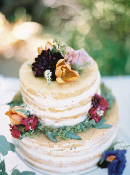 A two-tiered wedding cake with colorful floral decorations
