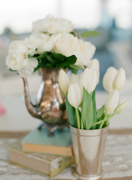 Elegant floral arrangement featuring white tulips and flowers in silver vessels