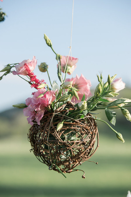 Hanging floral arrangement of pink flowers in a woven basket