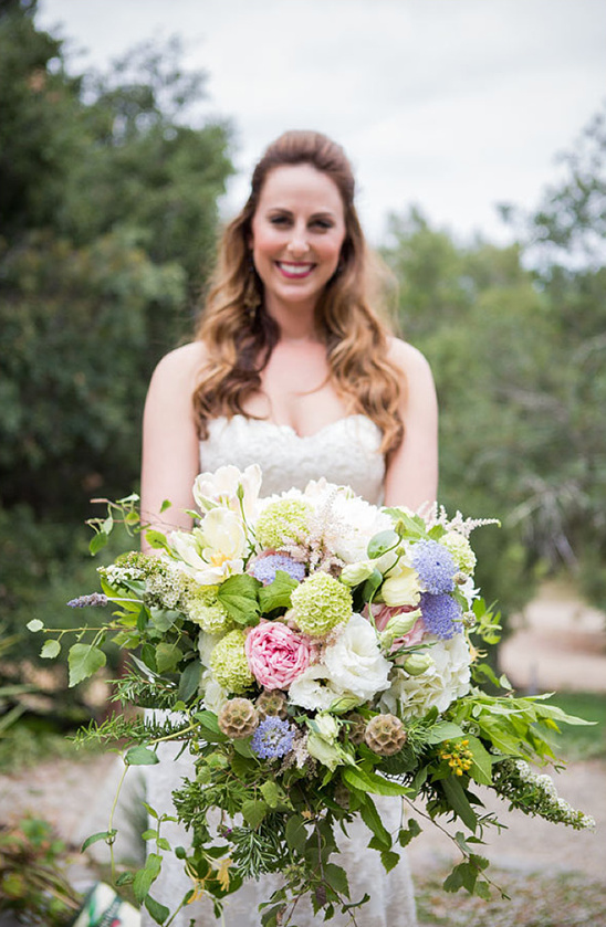 Happy bride holding a beautiful wedding bouquet smiling at the camera