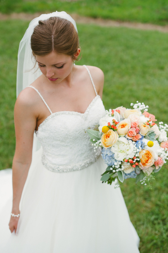Beautiful bride in white dress holds a colorful wedding bouquet