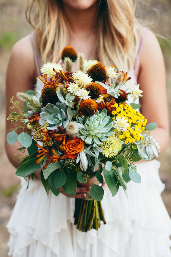 Bride holding a vibrant, rustic wedding bouquet of mixed flowers