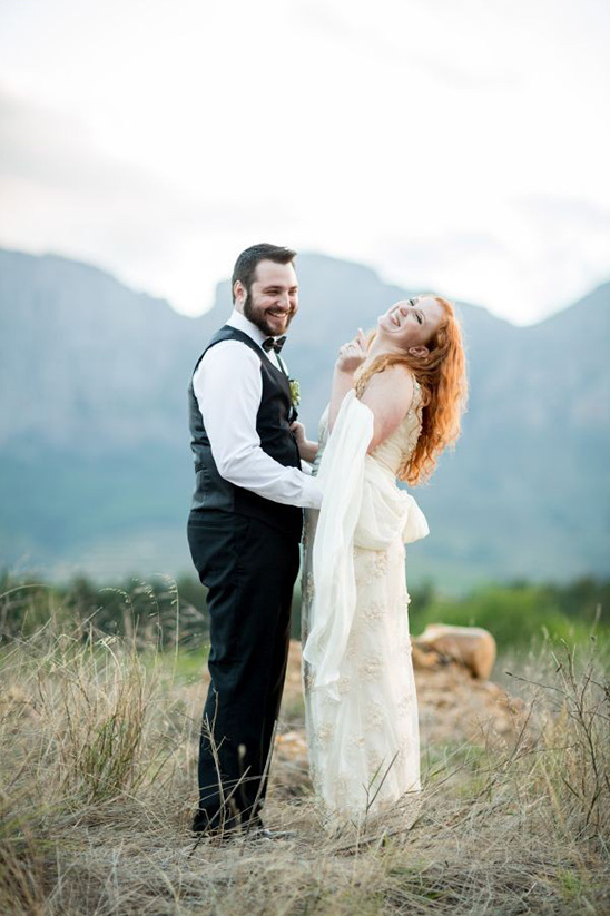 Happy bride and groom laughing in scenic outdoor wedding photo