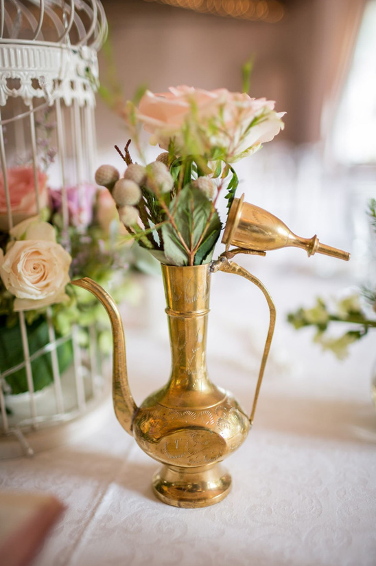 Golden brass pitcher with floral arrangement on a table