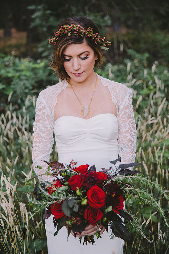 Bride with red roses bouquet and berry wreath outdoors