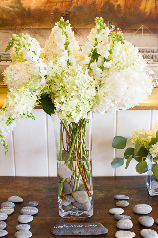Elegant wedding table decor with white flowers in a vase and stones