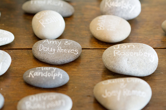 Wedding place cards written on smooth river rocks, names displayed
