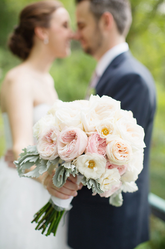 Bride and groom holding wedding bouquet of pink and white roses