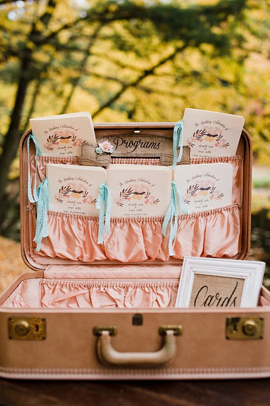 Vintage suitcase wedding decor with programs and a card sign