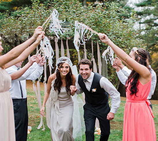 Newlyweds exit wedding ceremony surrounded by cheering guests
