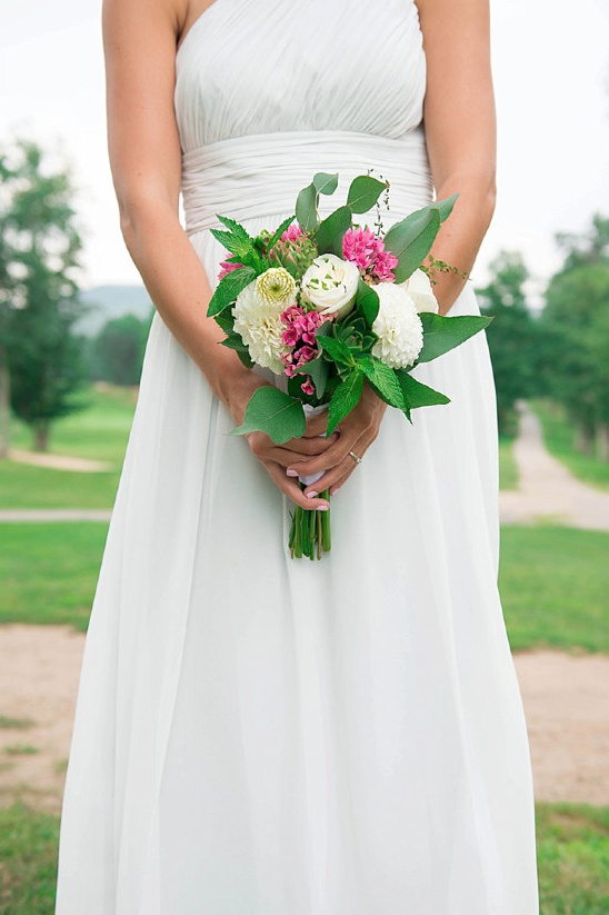 Bride holding a bouquet of flowers, standing in a beautiful landscape
