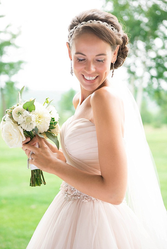 Happy bride holding bouquet, wearing a wedding dress