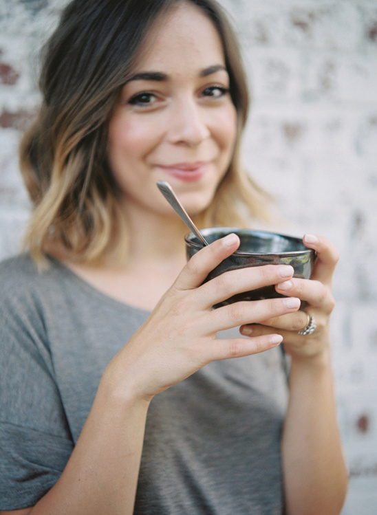 Woman smiling while holding bowl and spoon outdoors