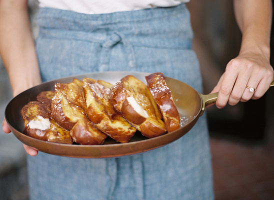 Fresh french toast in a pan held by person in apron