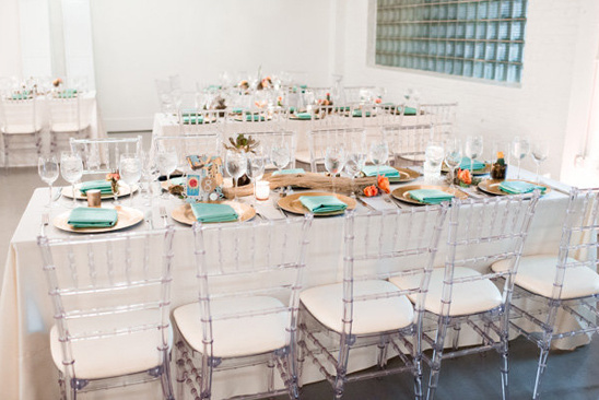 Elegant reception table with transparent chairs and gold plates