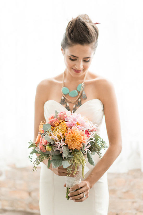 Smiling bride with colorful bouquet in white wedding dress