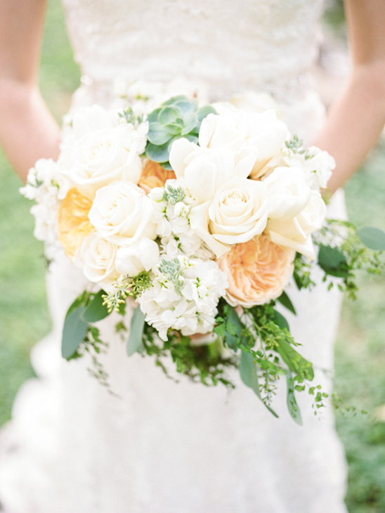Bride holds a beautiful white and peach rose bouquet