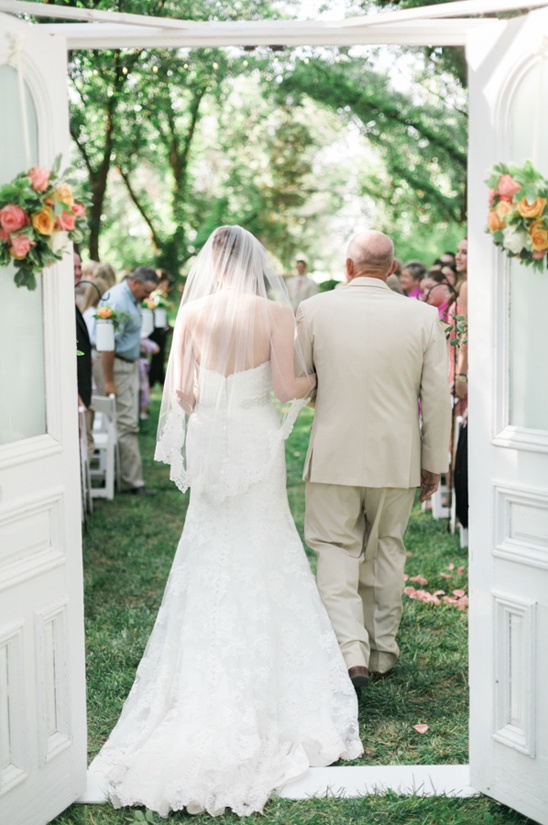 Bride walks down the aisle with her father at outdoor wedding