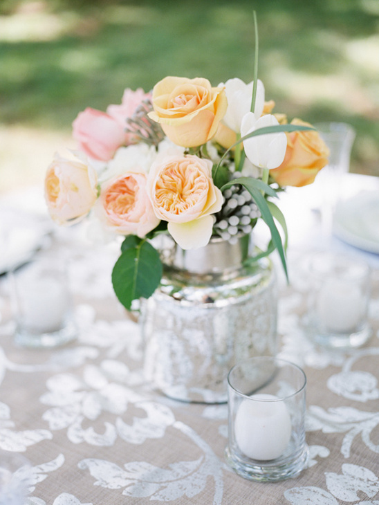 Floral centerpiece of peach and white roses in silver vase