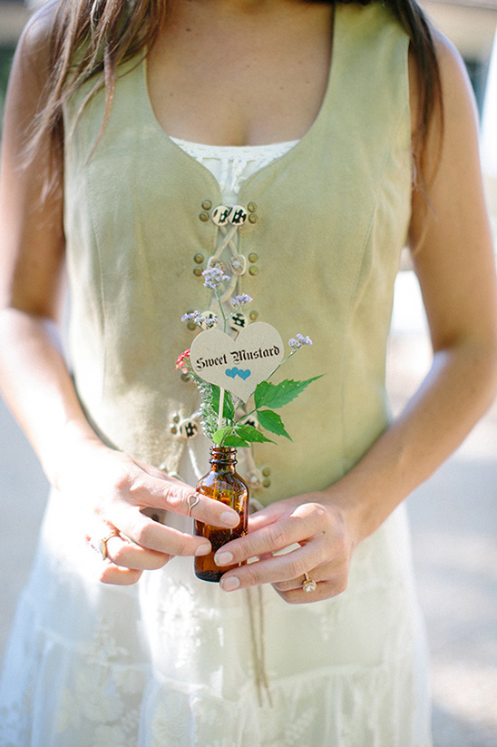 Woman holding flowers in a bottle wearing vest and dress