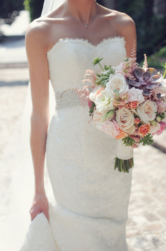 Bride in lace gown holds a stunning succulent bouquet