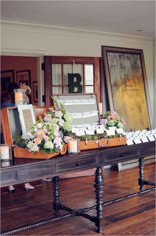 Wedding seating cards displayed in floral suitcases