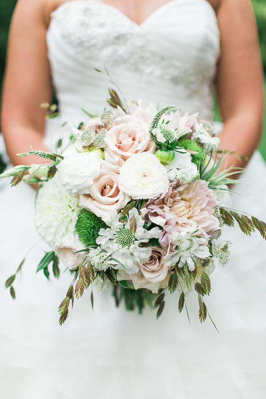 Bride holds pastel pink white wedding flower bouquet