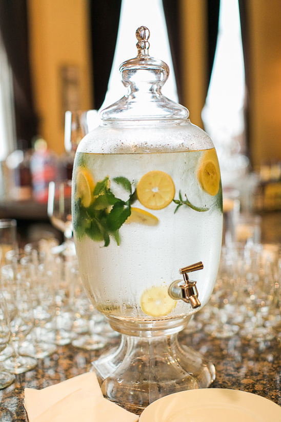 Elegant glass drink dispenser filled with lemon water at an event