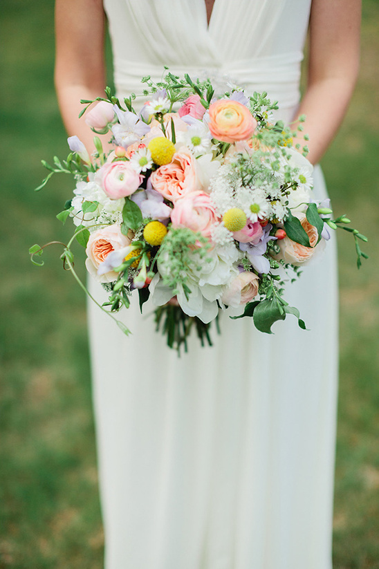Bride in white dress holding colorful flower bouquet