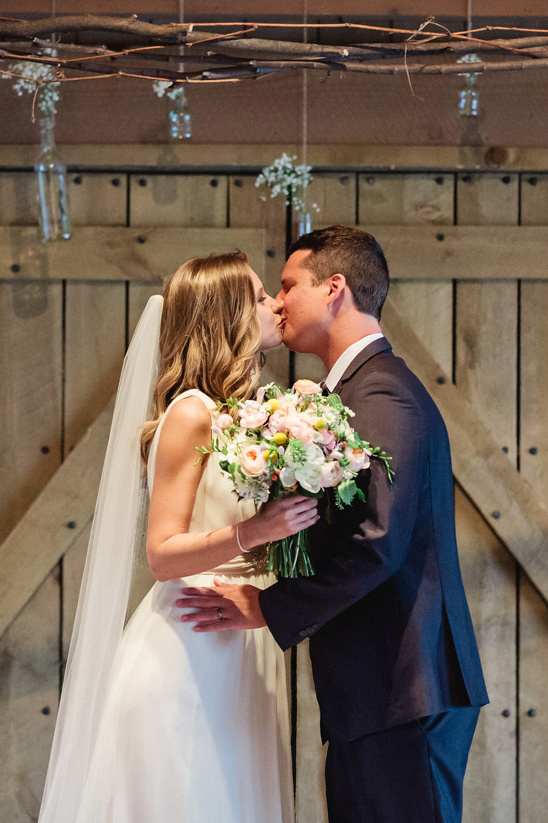 Bride and groom sharing a kiss at their barn wedding