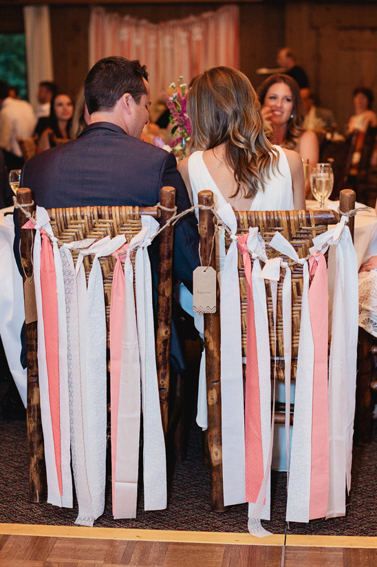 Wedding couple at their table, backs to camera with decorated chairs