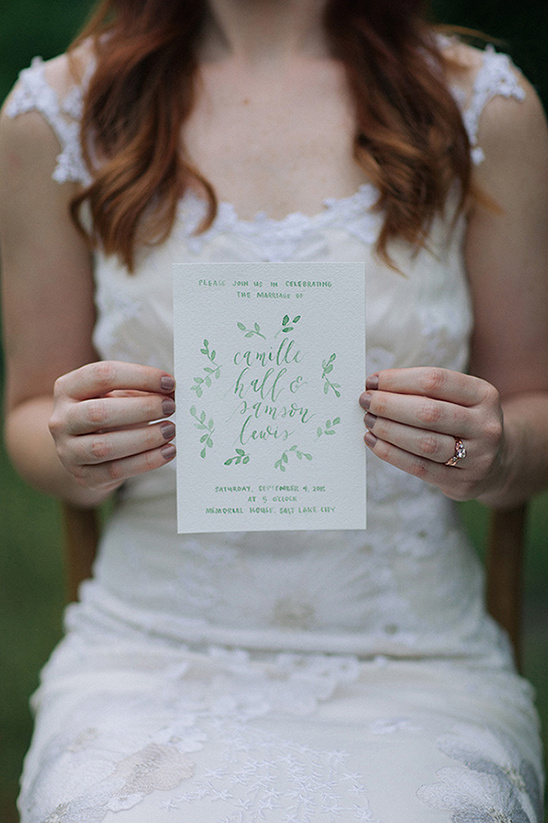 Bride holds wedding invitation for Camille and Samson