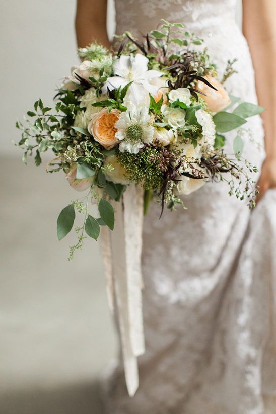 Bride holds lush white and peach wedding flower bouquet