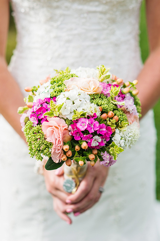 Bride in white holds vibrant colorful flower bouquet