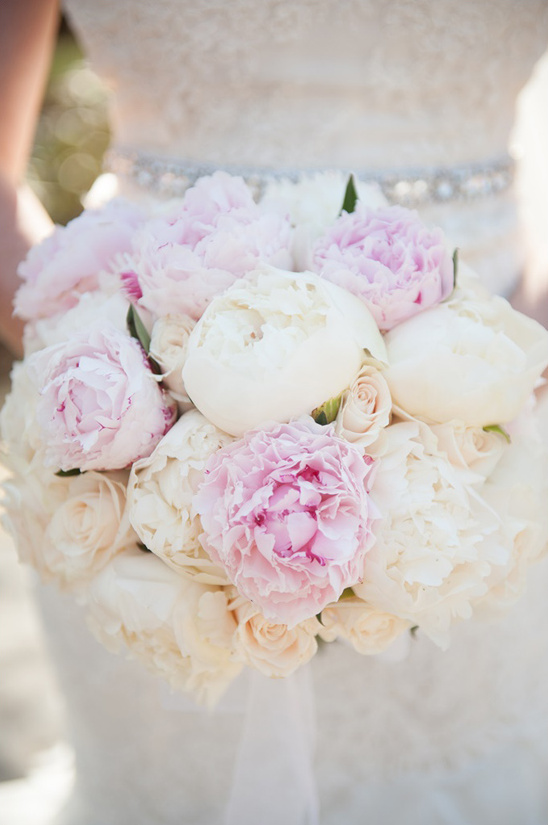 Bride holding peony and rose wedding bouquet closeup