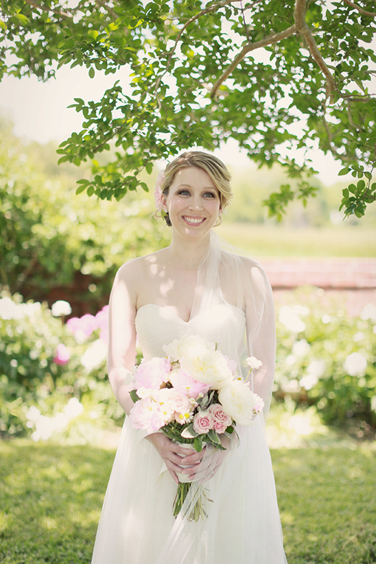 Smiling bride with flower bouquet in garden setting